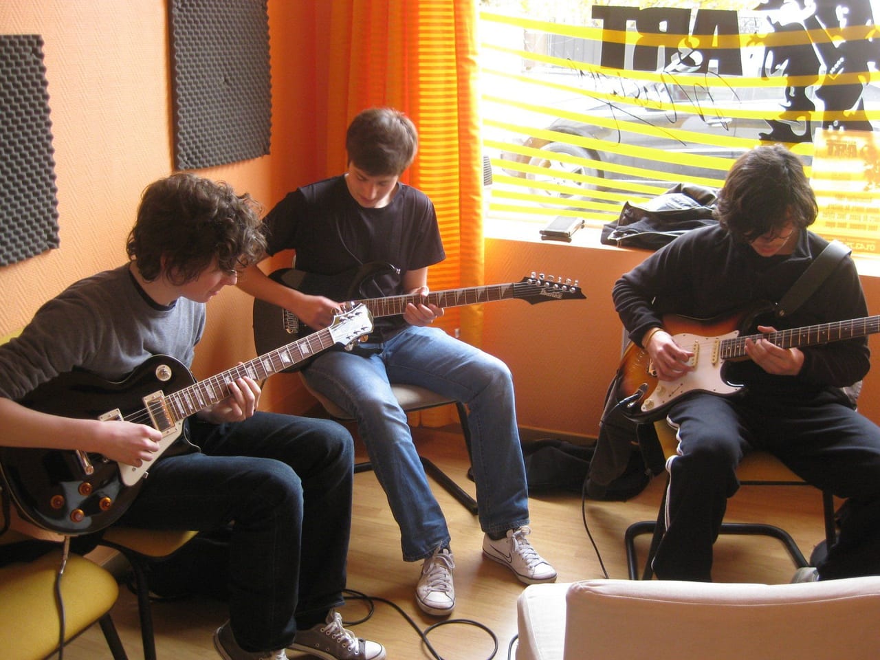 Atelier collectif : des adolescents jouent de la guitare ensemble.